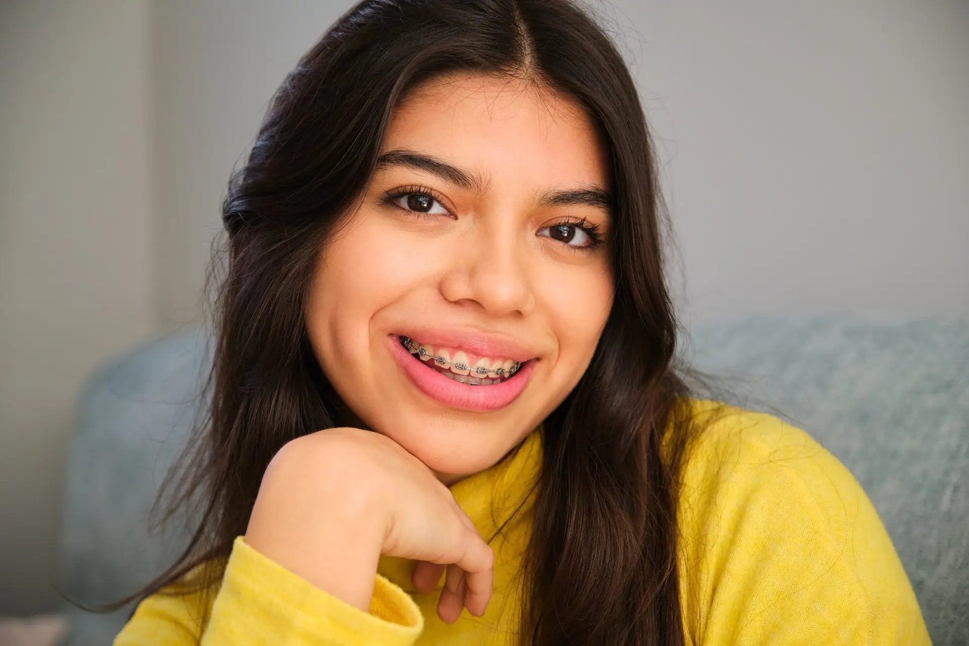 Smiling teen girl with braces in a yellow sweater