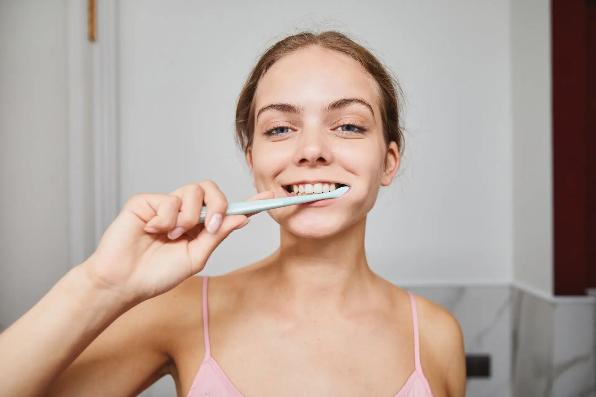 Young woman smiling while brushing her teeth