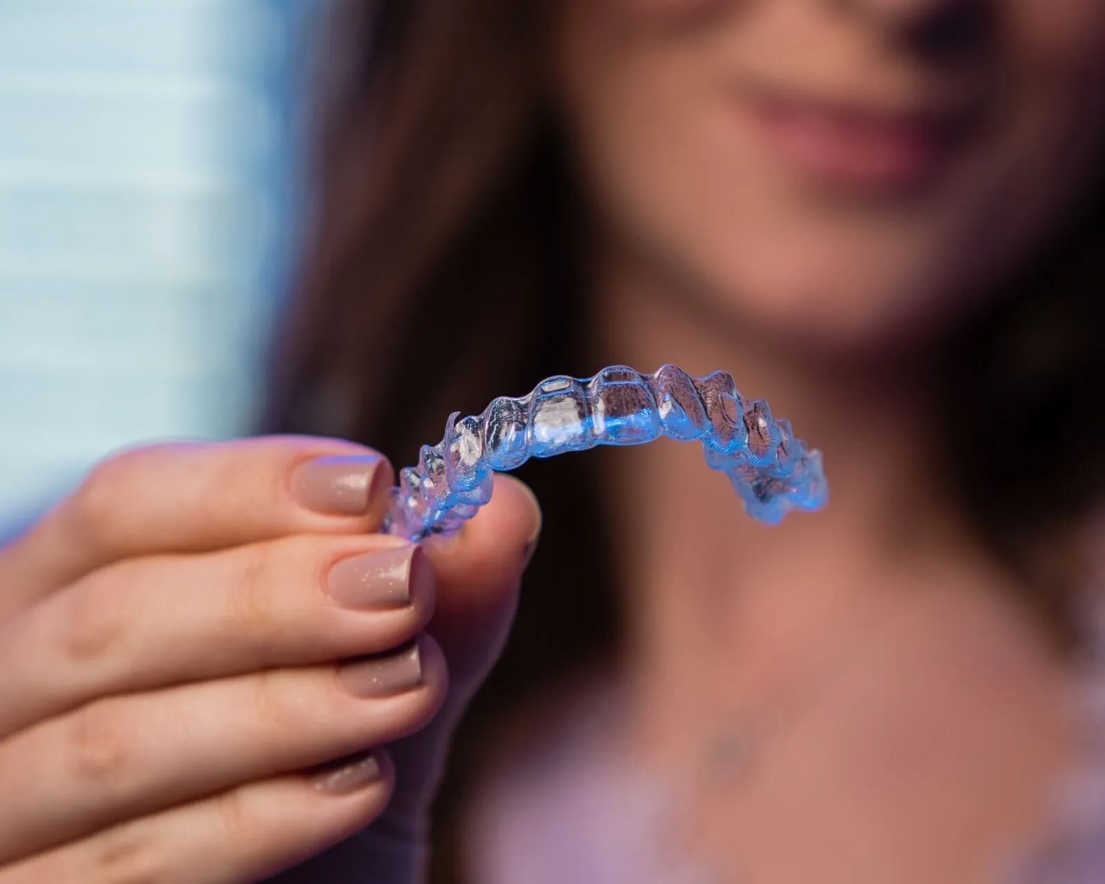 Woman holding the clear aligner she just took out